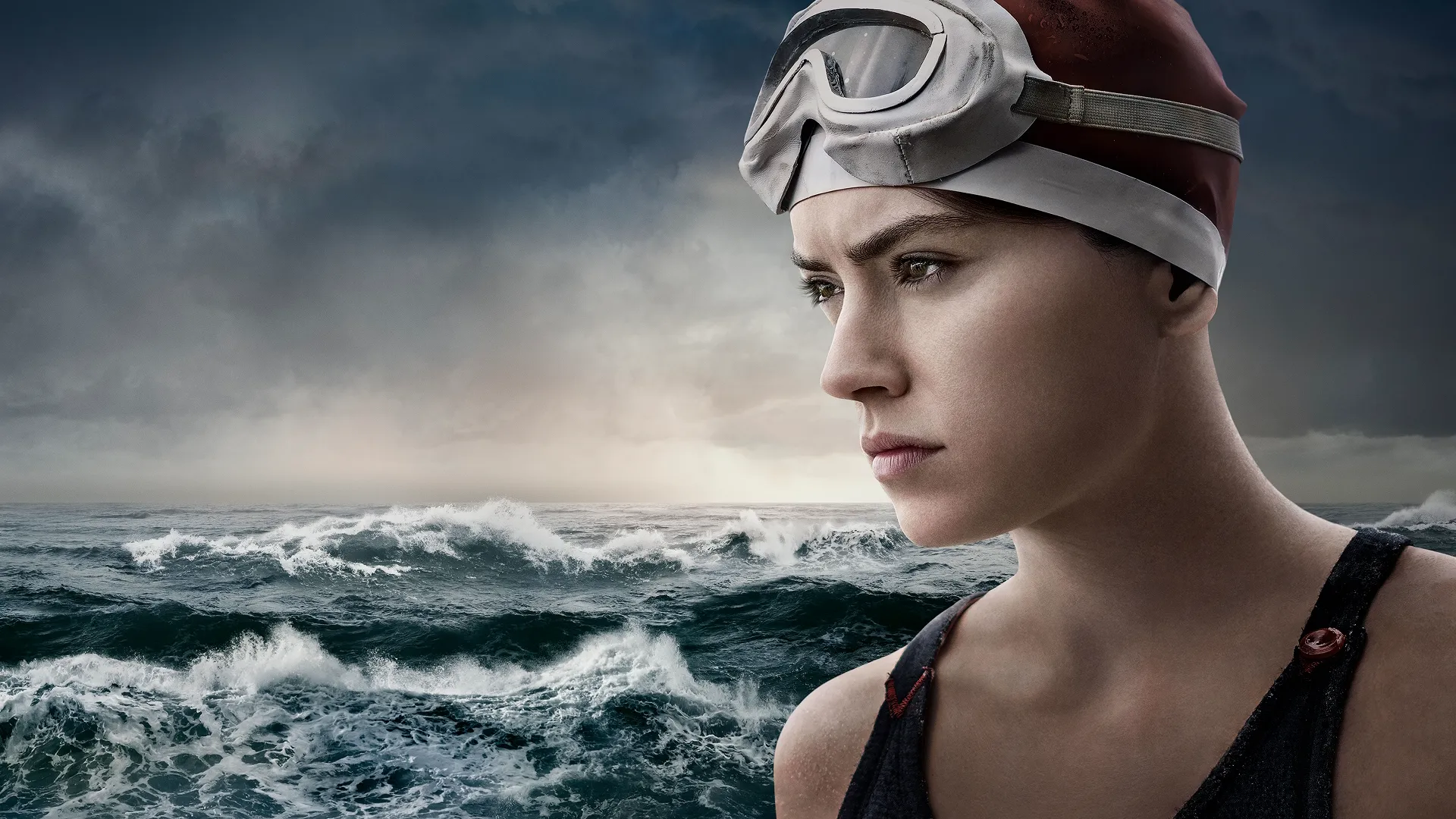 Trudy Ederle (Daisy Ridley) wearing a swimming cap and goggles with the sea as a backdrop.