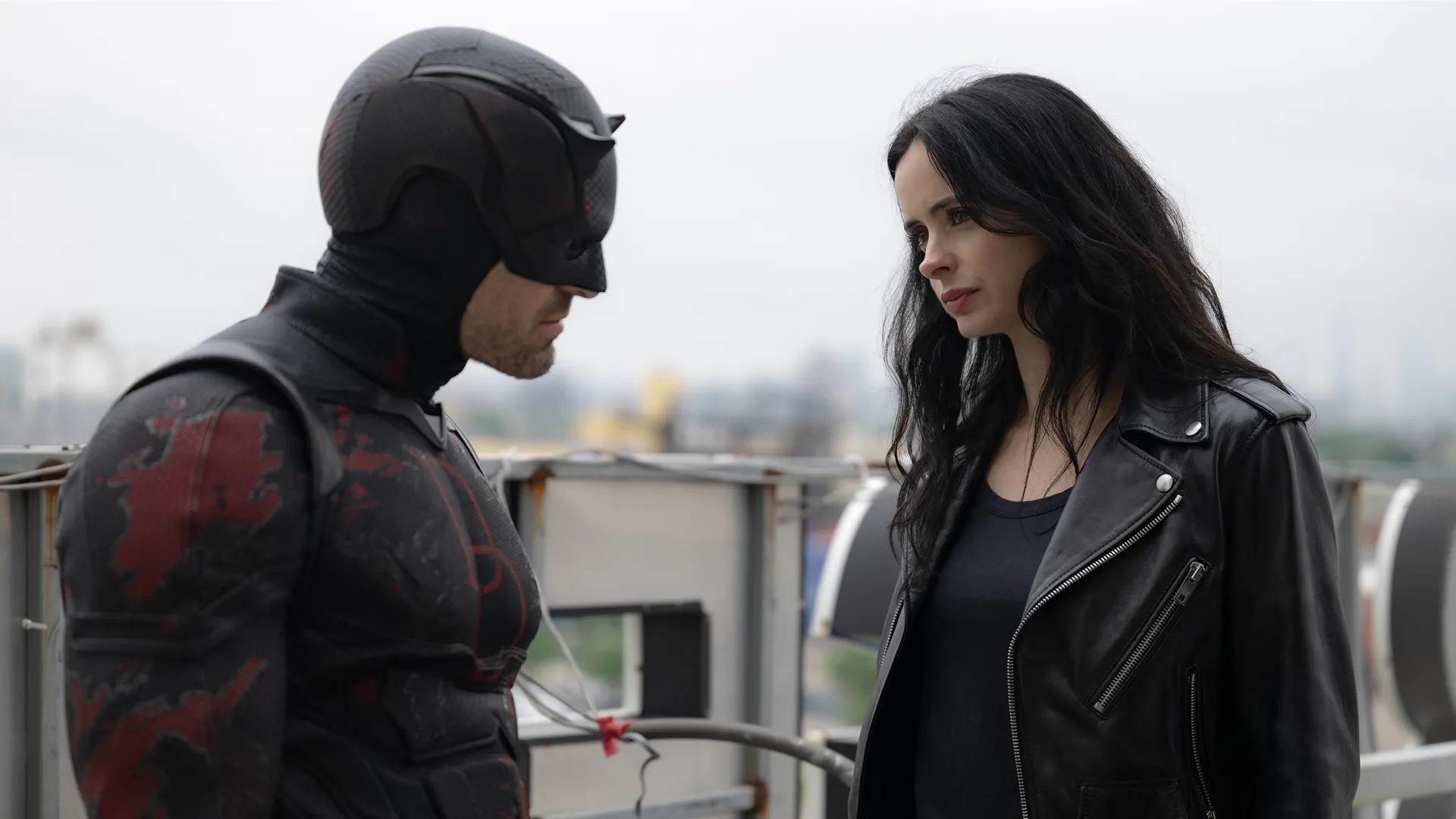 Daredevil (Charlie Cox) and Jessica Jones (Krysten Ritter) strategize on a rooftop.