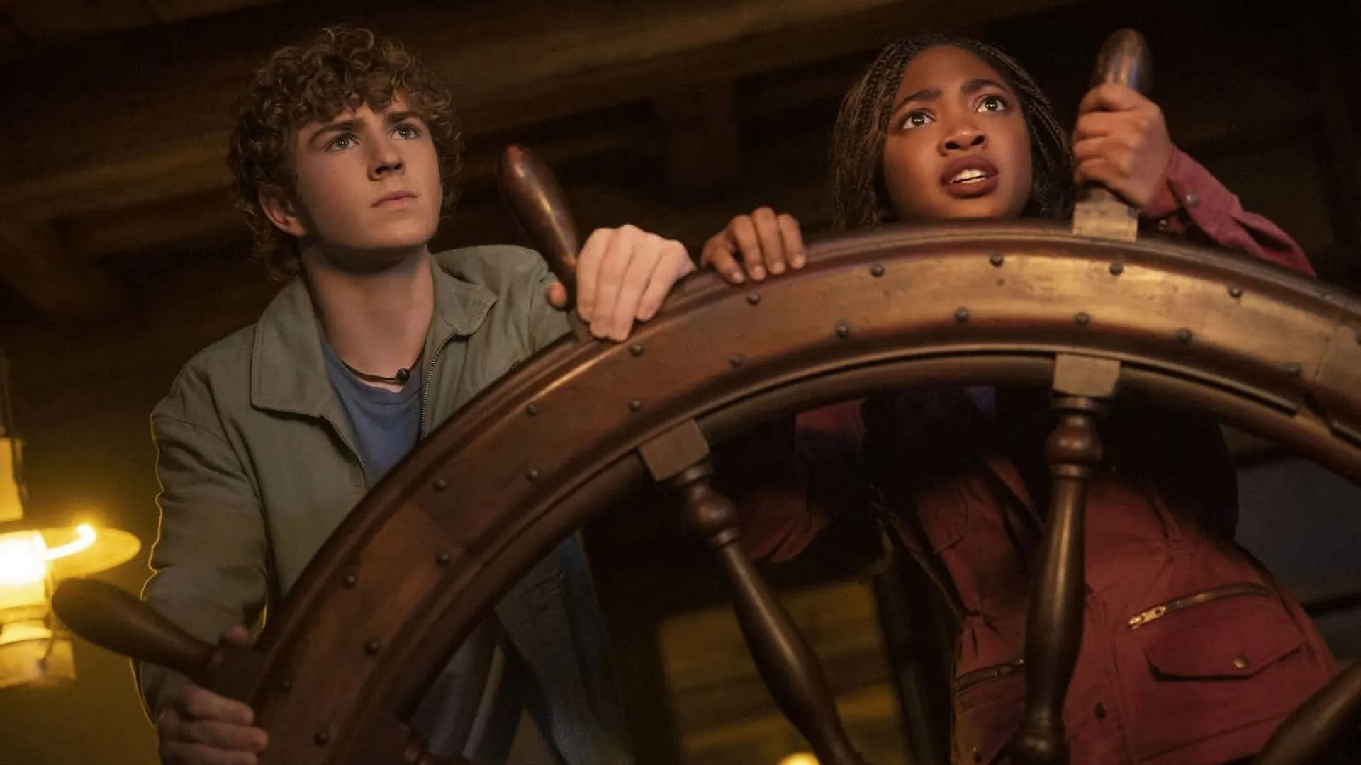 Percy Jackson (Walker Scobell) and Annabeth Chase (Leah Jeffries) hold on to the helm of a ship