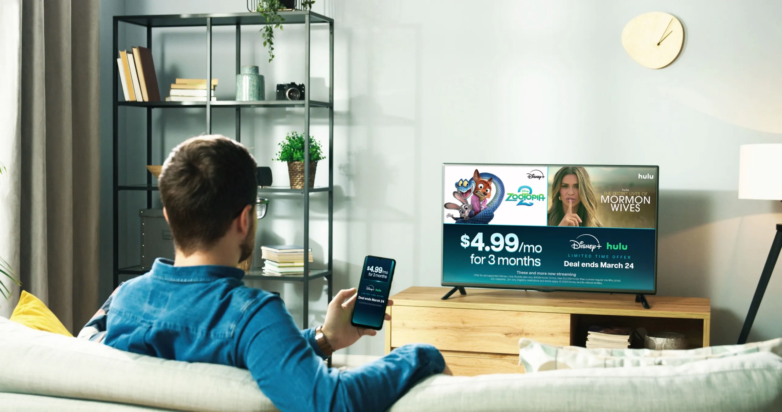 Man watching television in his living room, the TV showcases the $4.99/mo for 3 months bundle offer and available titles such as Zootopia 2 (Disney+) and Secret Lives of Mormon Wives (Hulu).