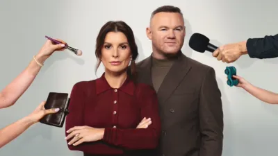 Wayne Rooney and Coleen Rooney pose together as hands hold a microphone, makeup brush, notebook and toy car in The Real Rooneys.