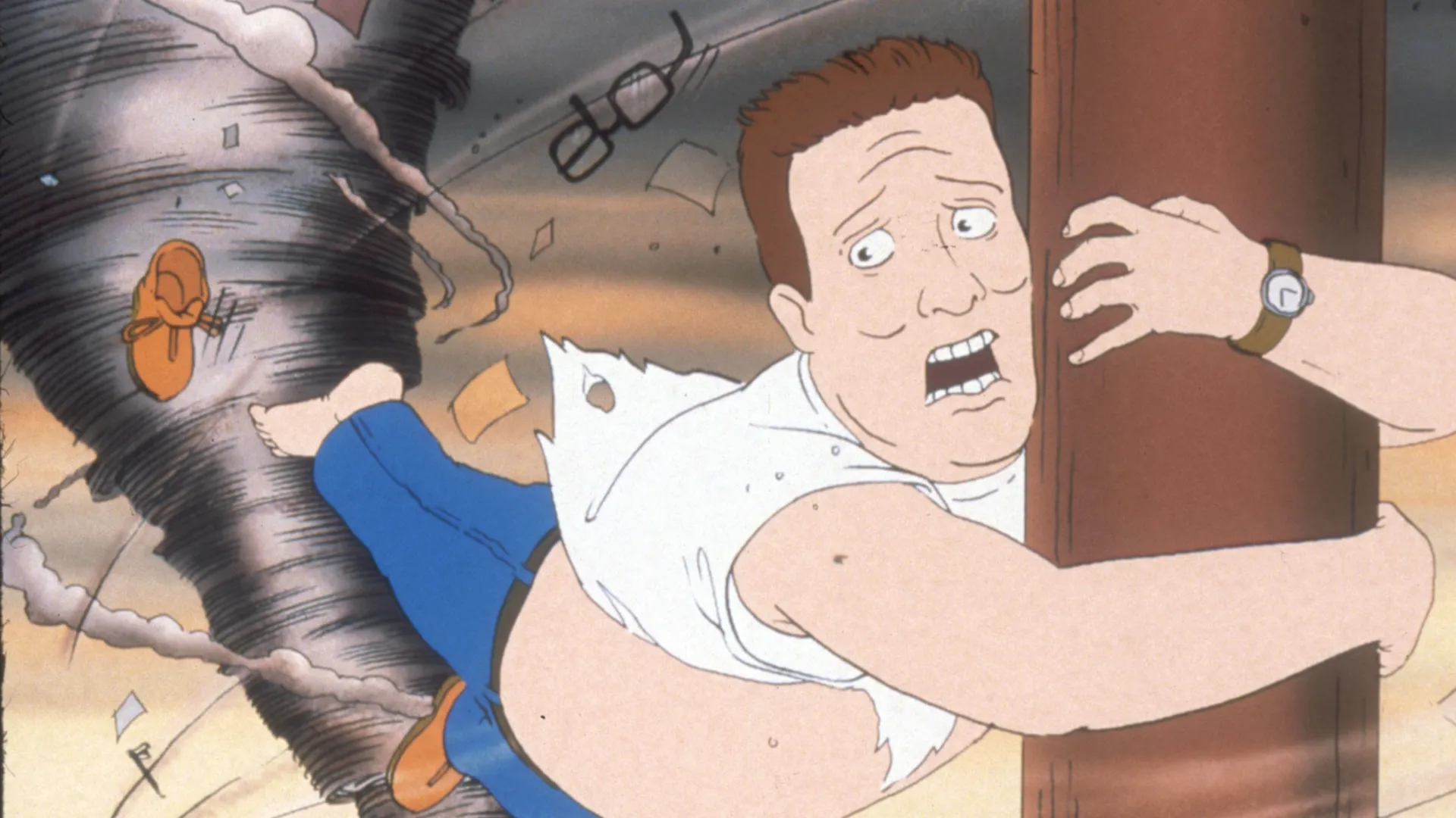 Hank (Mike Judge) clings to a wooden post as a tornado tears through the building behind him.
