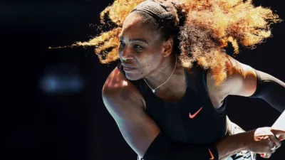 Professional tennis player prepares to serve during a competitive match.