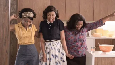 Taraji P. Henson, Octavia Spencer, and Janelle Monáe celebrating together in a scene from the Black history movie Hidden Figures.