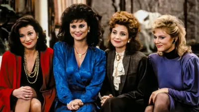 The main cast of the 1980s sitcom Designing Women sitting together, featuring the four women of Sugarbaker & Associates dressed in colorful ’80s fashion.