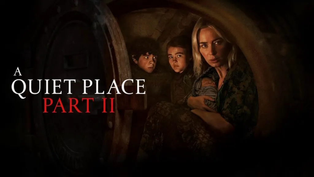 Poster for A Quiet Place Part II showing Emily Blunt holding a baby while hiding with two children inside a dimly lit metal chamber, with the film title displayed beside them.