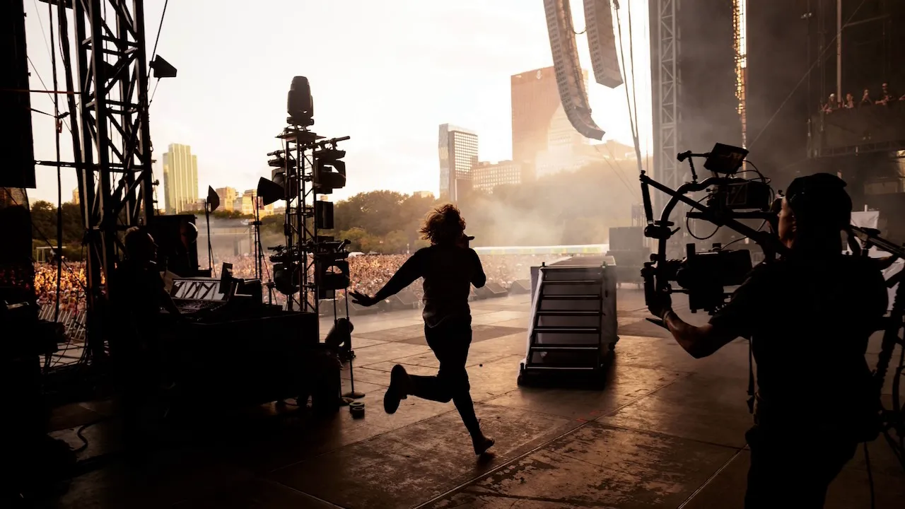 The Kid LAROI performs onstage at Lollapalooza with the Chicago skyline and festival crowd in the background.