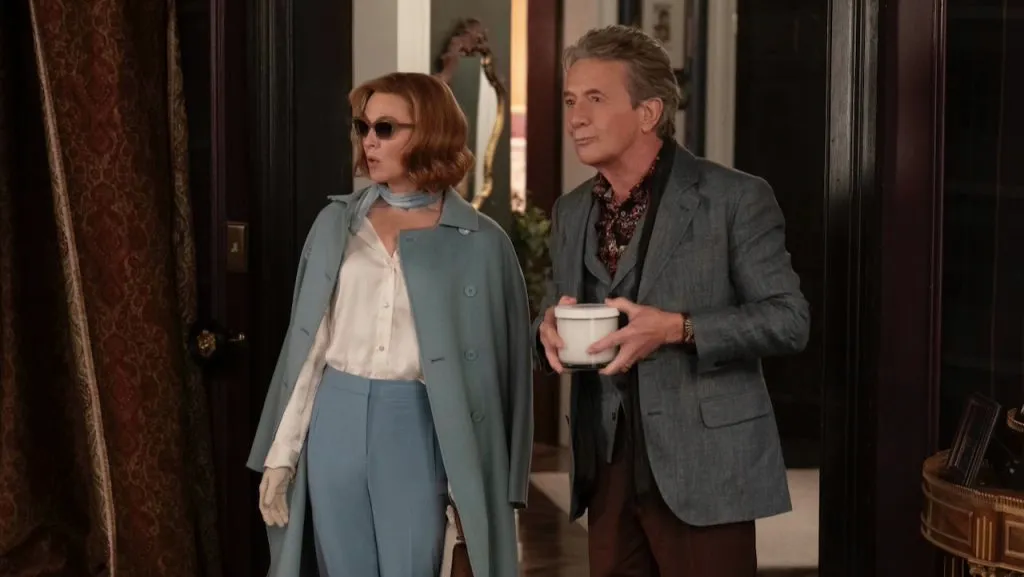 Renée Zellweger, wearing a light blue coat and sunglasses, stands beside Martin Short.