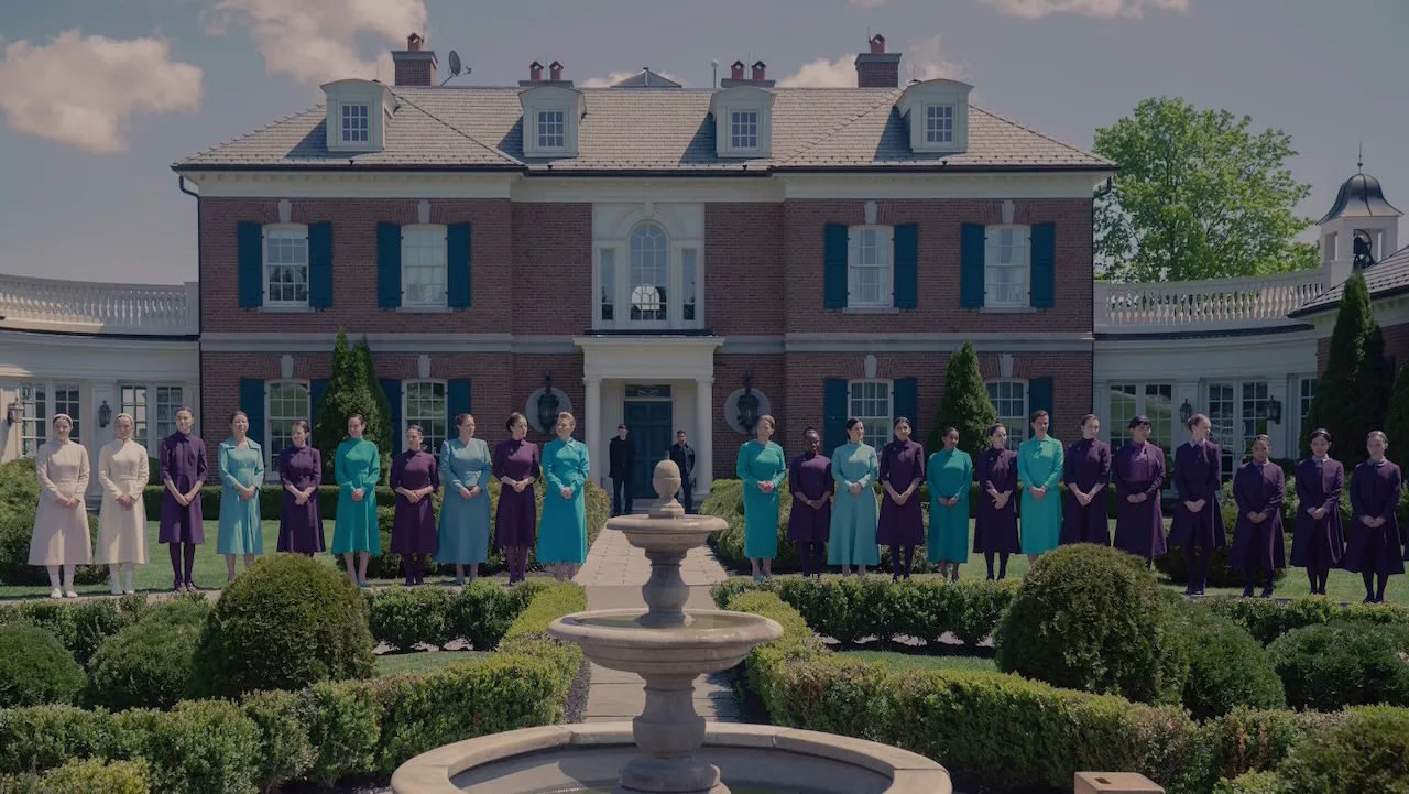 Women in color-coded uniforms stand in formation outside a large estate in Gilead, as seen in The Testaments on Hulu.
