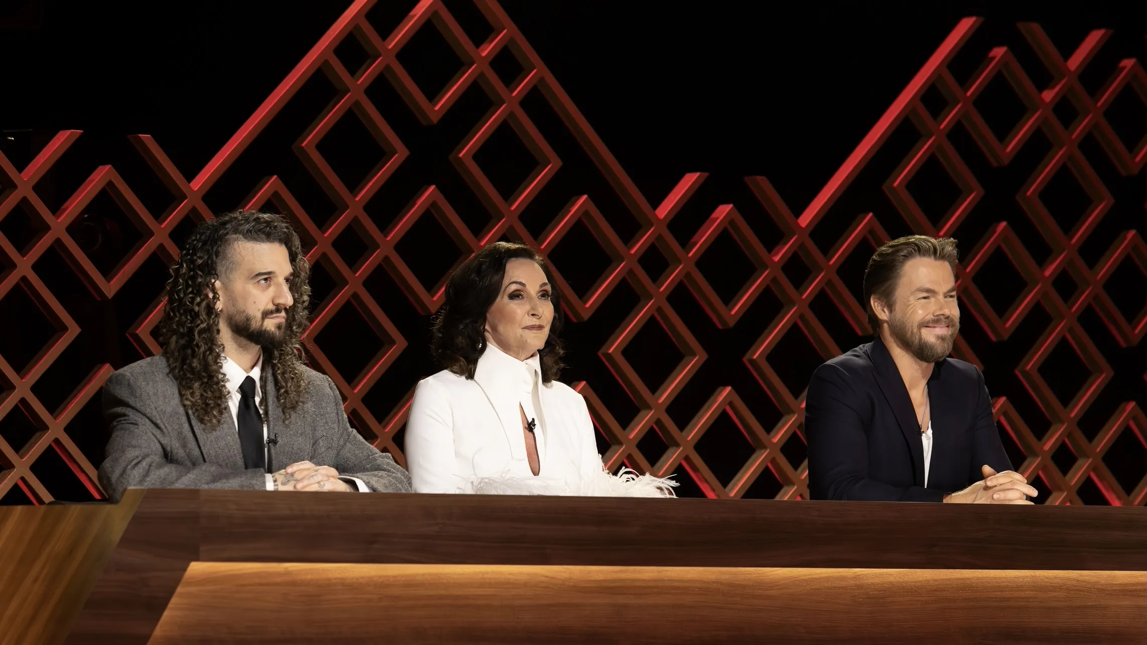 Mark Ballas, Shirley Ballas, and guest judge Derek Hough sit behind the judges table during Dancing With the Stars: The Next Pro.