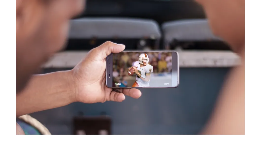 Person watching college football on a smartphone.