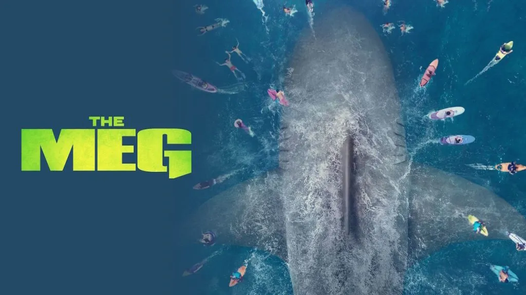 Poster for The Meg showing an enormous shark seen from above swimming toward a group of surfers and swimmers in the ocean, with the movie title in bold green letters on the left.