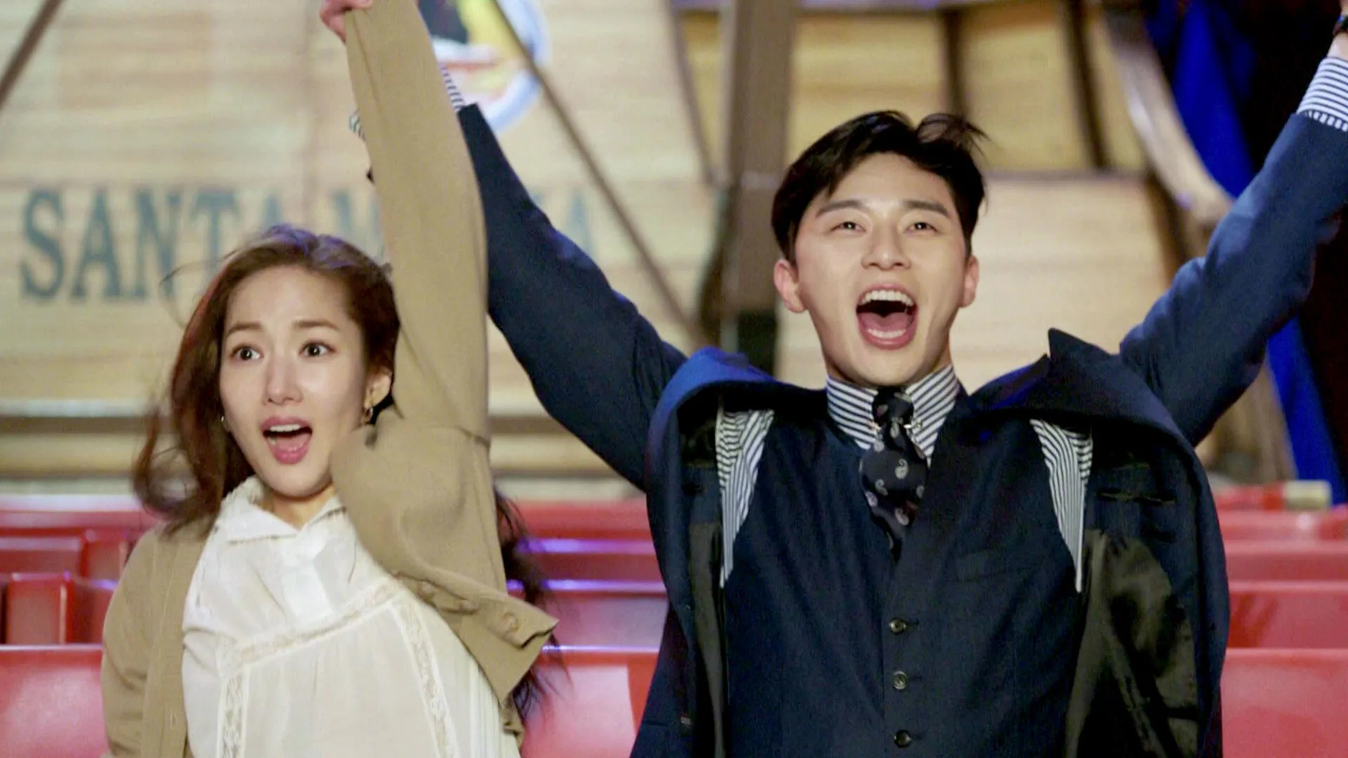 A man and woman raise their arms in celebration in a scene from the Korean drama What’s Wrong With Secretary Kim.