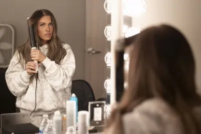 Jessi Ngatikaura styles her hair in front of a mirror.
