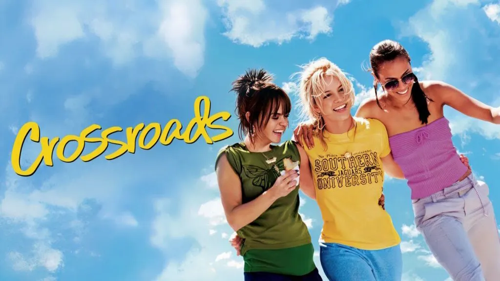 Title art for Crossroads showing three friends walking arm-in-arm under a bright blue sky, smiling and laughing together.