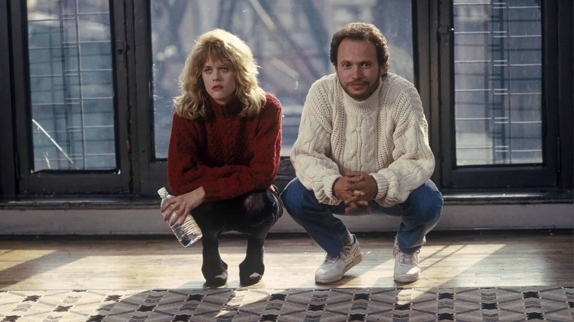 A scene from When Harry Met Sally shows two people crouching on an apartment floor in front of large windows, dressed in sweaters and jeans.